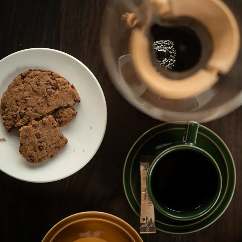Kuntrawant Kaffee in grüner Tasse serviert mit Schokokeksen im Gastronomie-Ambiente